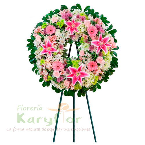 Corona de condolencias elaborado en tripode con finas rosas, lilium, gerberas, variedad de flores y follaje. Se puede elaborar en distintos colores de rosa previa coordinacion.